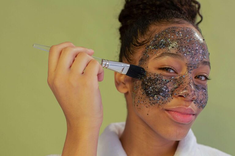 close up of beautiful young woman applying a face mask treament containing glitter. What is an everything shower meaning everything shower. Everything shower list. everything shower routine. everything shower meaning. luxury shower. luxury shower routine.