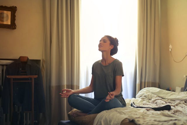 young woman meditating on her bed. Morning routine ideas. morning routine checklist. how to create a morning routine. how to start a morning routine. what is the best morning routine.