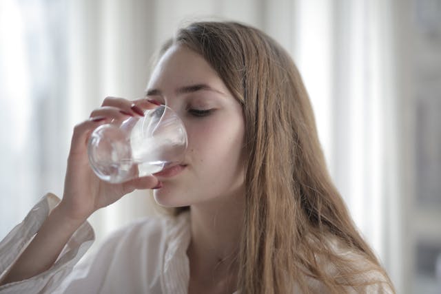 young woman drinking water. Morning routine ideas. morning routine checklist. how to create a morning routine. how to start a morning routine. what is the best morning routine.