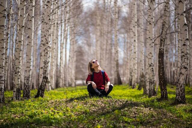 woman sitting crossed legged in a forest looking up. weekend reset. weekend reset routine. wellness retreat. Bedroom retreat ideas. wellness retreat. home retreat ideas. Refreshed. self care weekend. self care weekend ideas. how to have a self care weekend.