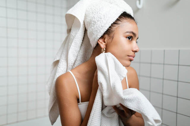 young woman patting her face dry with a towel. weekend reset. weekend reset routine. wellness retreat. Bedroom retreat ideas. wellness retreat. home retreat ideas. Refreshed. self care weekend. self care weekend ideas. how to have a self care weekend.