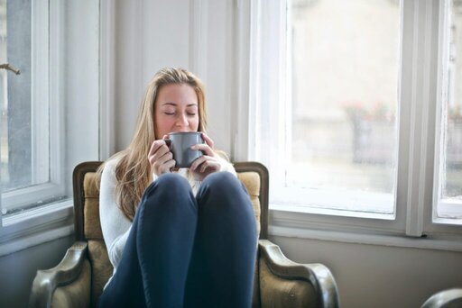 woman relaxing in a chair with a cup of tea. Hangover breakfast ideas. hangover skin. how to fix a hangover quick. how to treat dehydrated skin. how to fix dehydrated skin. tired when hungover. re energize.