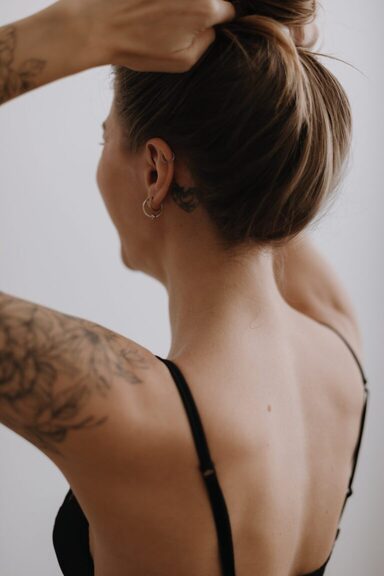 back of a woman styling her hair into a bun. Morning routine ideas. morning routine checklist. how to create a morning routine. how to start a morning routine. what is the best morning routine.