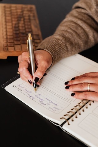 close up of a womans hands writing notes. 