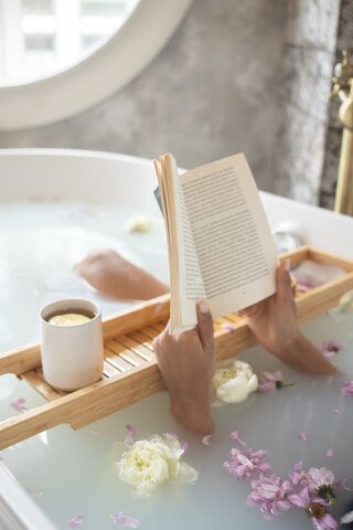 close up of hands holding a book being read in a bathtub. good habits. good habits examples. what are good habits. what is one of the core habits practiced by the most successful people? non negotiable examples. Work life balance tips. how to balance work and family life.