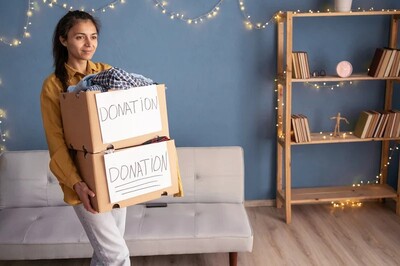 young woman carryng boxes to donate. How to declutter your home. declutter benefits.declutter clothes. how to declutter closet. declutter wardrobe. minimalist wardrobe. how to declutter clothes. how to declutter your closet. emma chamberlain. Underconsumption