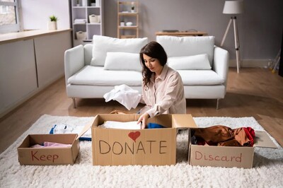 young woman dividing clothes to donate. How to declutter your home. declutter benefits.declutter clothes. how to declutter closet. declutter wardrobe. minimalist wardrobe. how to declutter clothes. how to declutter your closet. emma chamberlain. Underconsumption