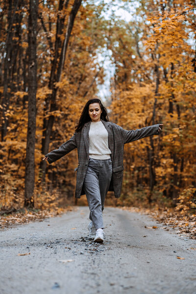 Woman, happy, walking on a path with trees on each side. Fall season, the leaves are brown. quick morning workout,
morning home workout,