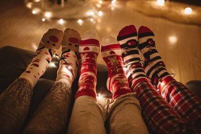 3 peoples feet wering Christmas socks. Christmas girls night. Christmas party. Christmas ladies night. holiday girls night. Christmas cocktails. girls night in. holiday party theme. ugly sweater party. 