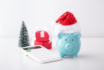 Christmas saving concept with piggy bank wearing christmas hat and calculator on white table. Surviving Christmas. Surviving Christmas. Self care and how to glow up. New Year's Eve. christmas self care. Stress-free Christmas season.